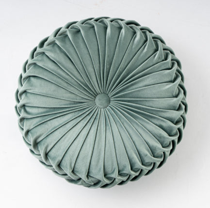 Round pleated cushion in a light green color on a white background