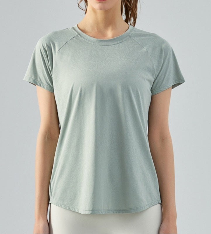 Woman wearing a jade green t-shirt on a light gray background
