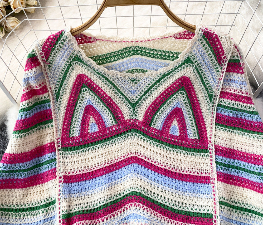 Colorful crocheted sweater on a hanger against a grid background