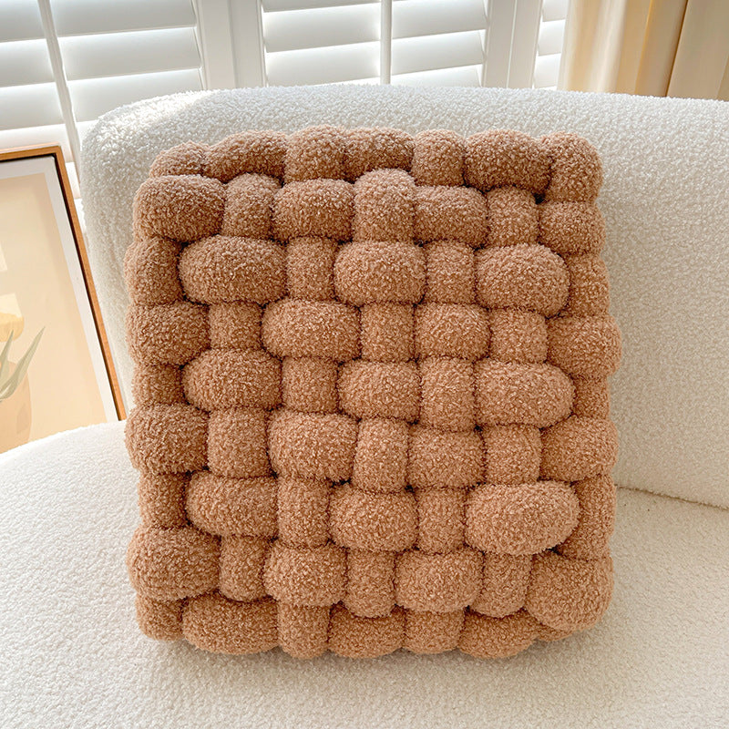 Brown woven cushion on a white chair with a neutral background