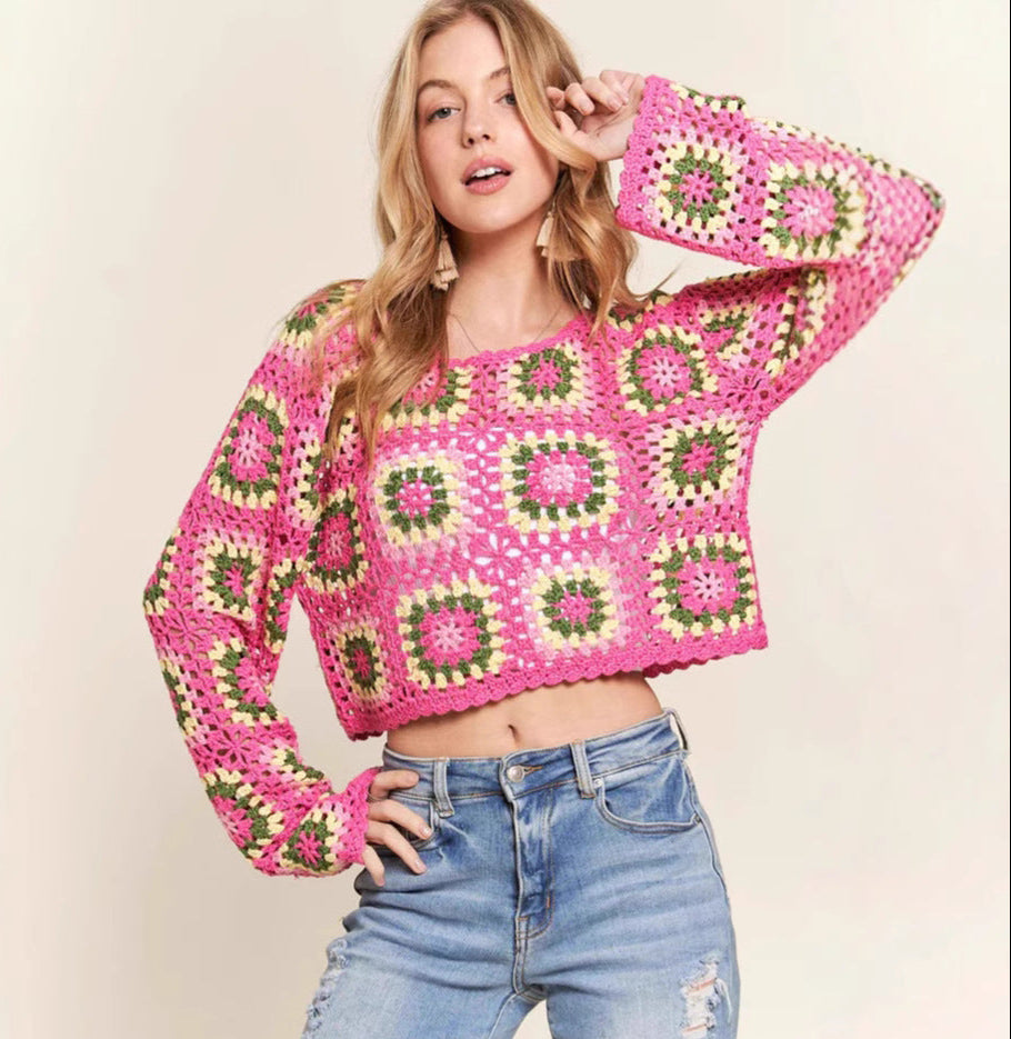 Woman wearing a pink and green patterned sweater with blue jeans on a beige background