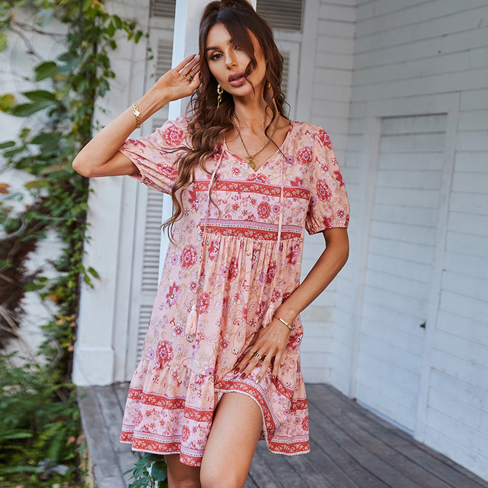 Woman wearing a pink floral dress standing on a wooden deck.