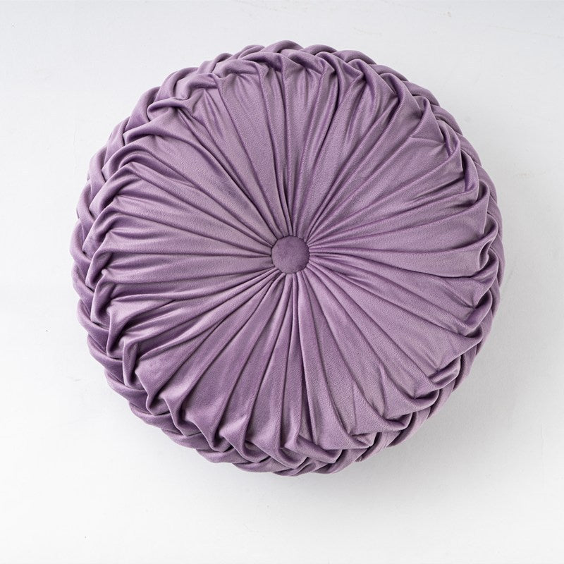 Round purple pillow with pleated texture on a white background