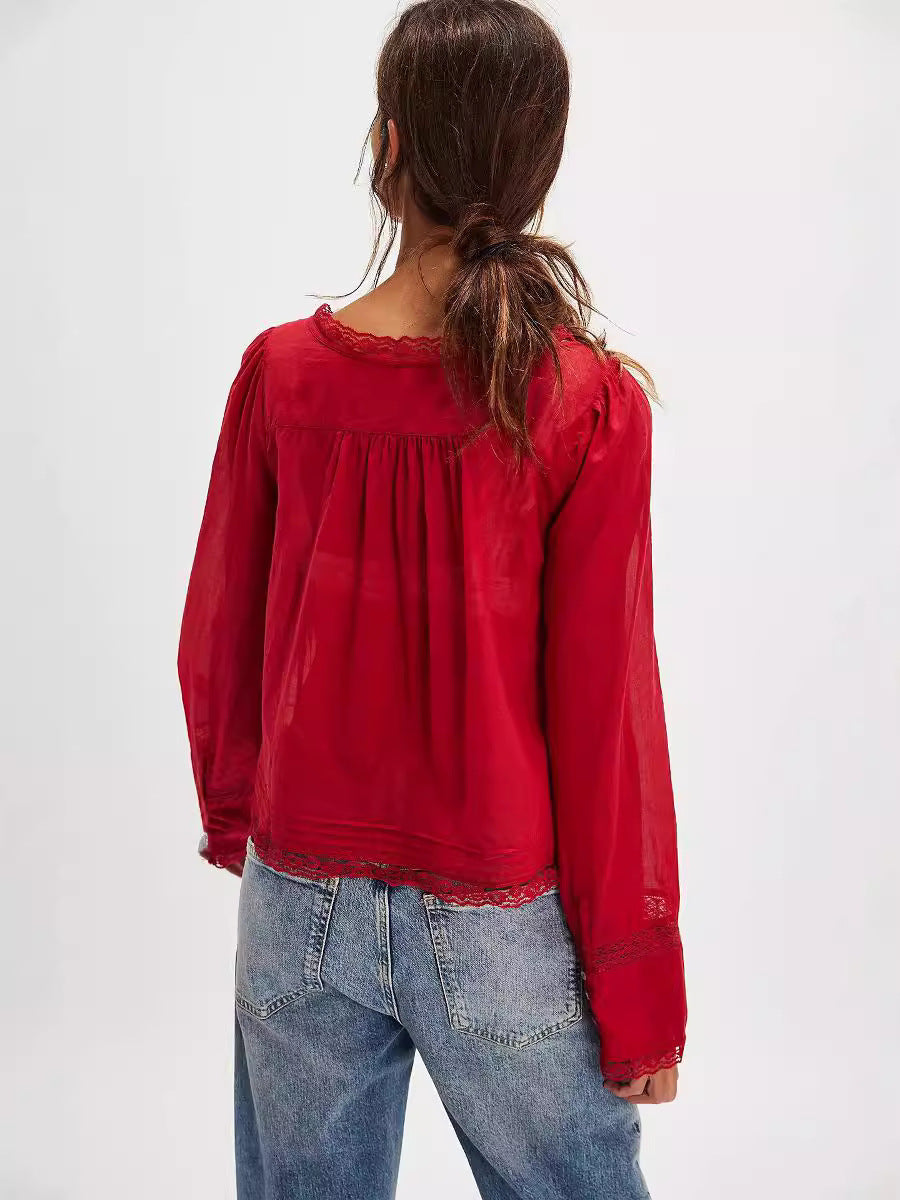 Person wearing a red blouse with lace details and blue jeans on a white background