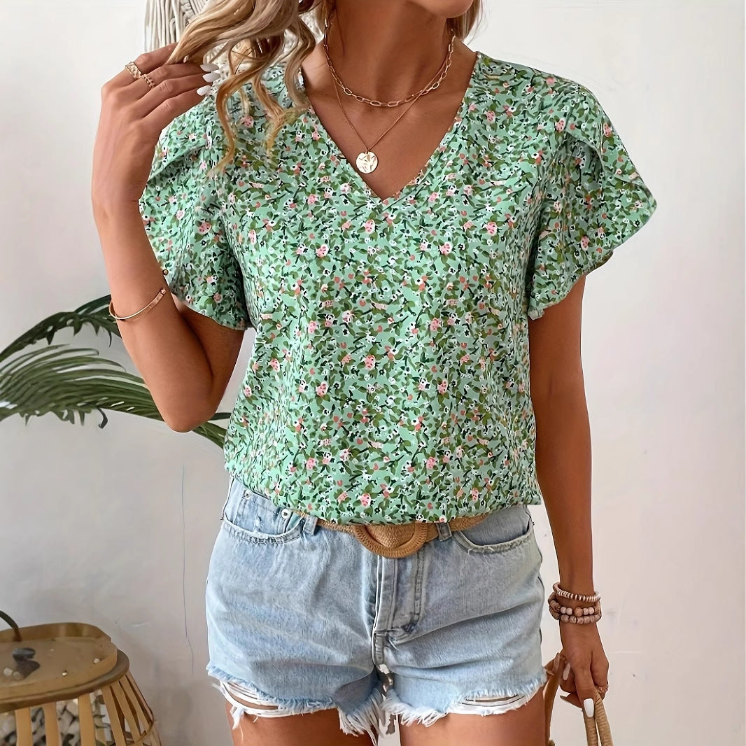 Woman wearing a green floral top and denim shorts against a white background