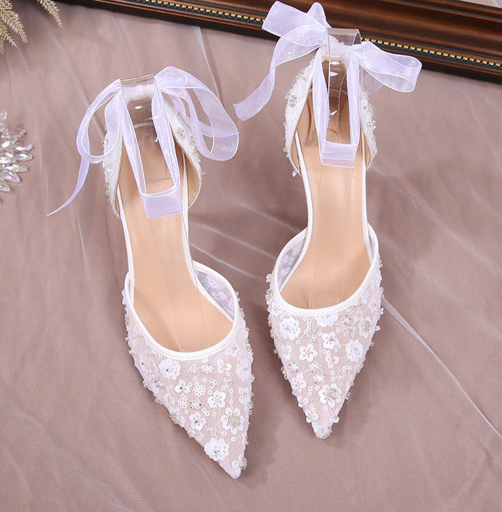 White lace wedding shoes with ribbons on a neutral background