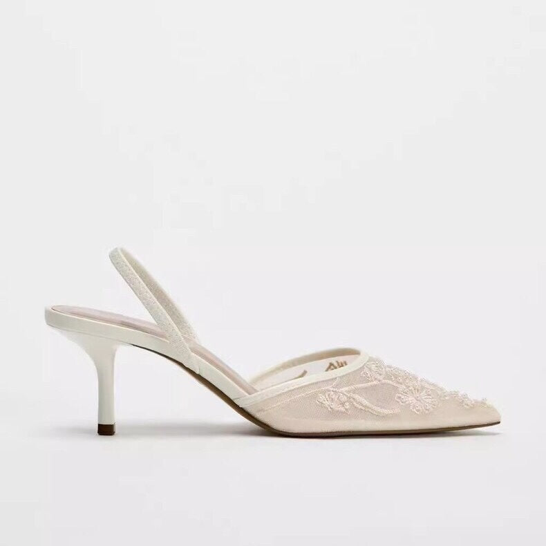 White sandal with thin strap on a light gray background