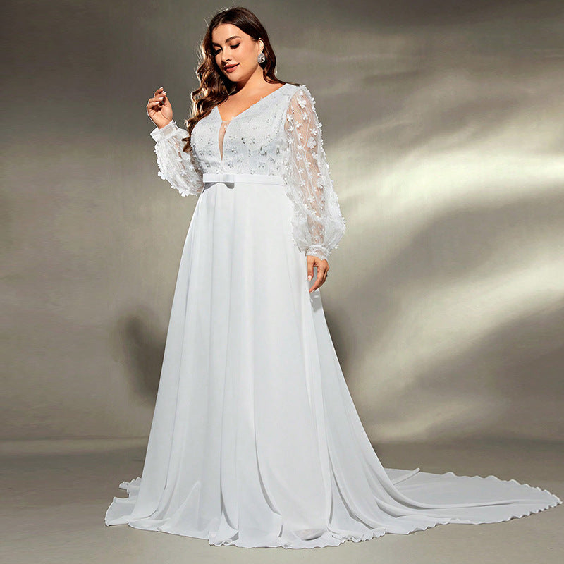 Woman wearing a white wedding dress with floral details on a neutral background