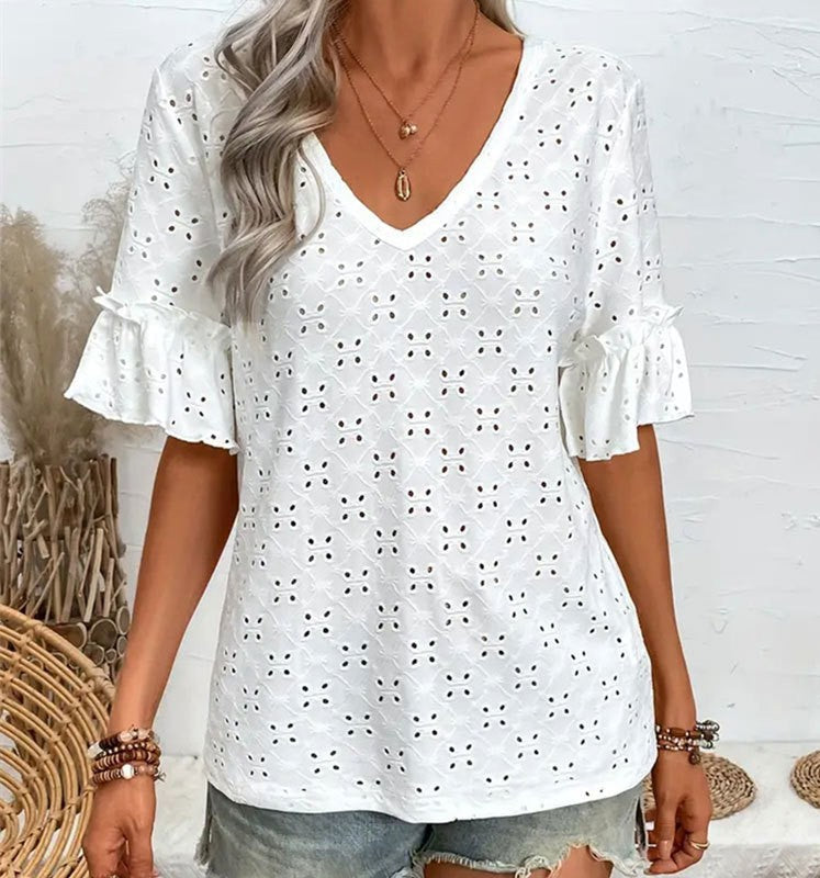 Woman wearing a white blouse with ruffled sleeves against a neutral background