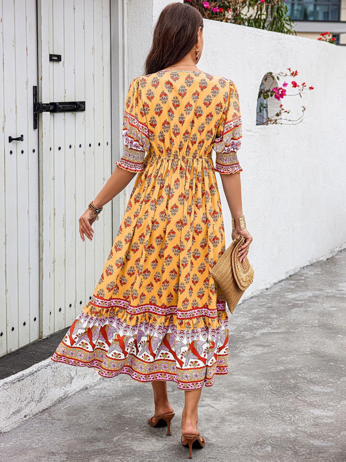 Woman wearing a yellow patterned dress walking on a street.