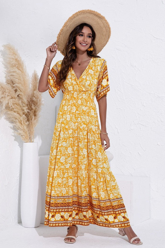 Woman wearing a yellow floral dress with a straw hat against a white background