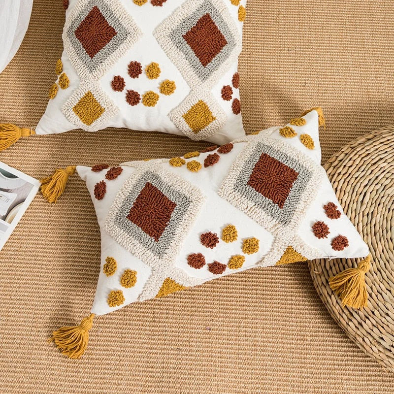 Decorative pillows with geometric patterns and tassels on a textured surface