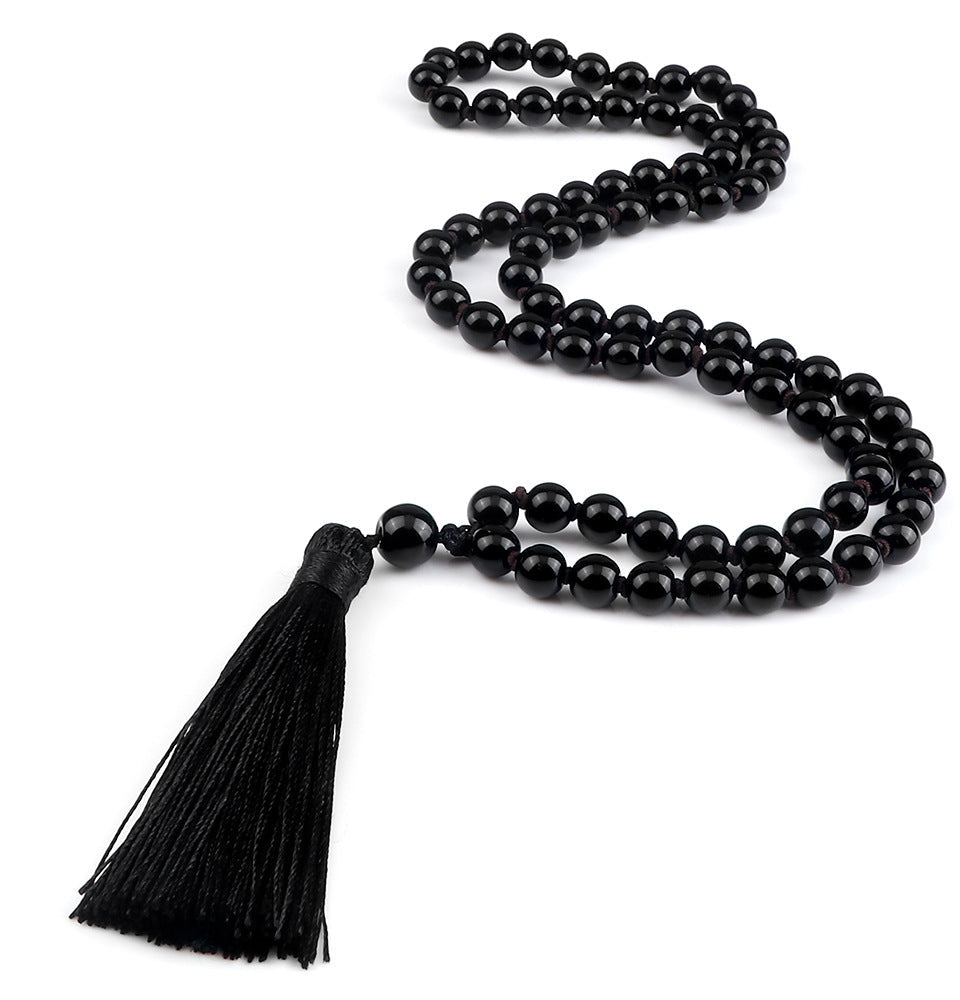 Black beaded necklace with a tassel on a white background