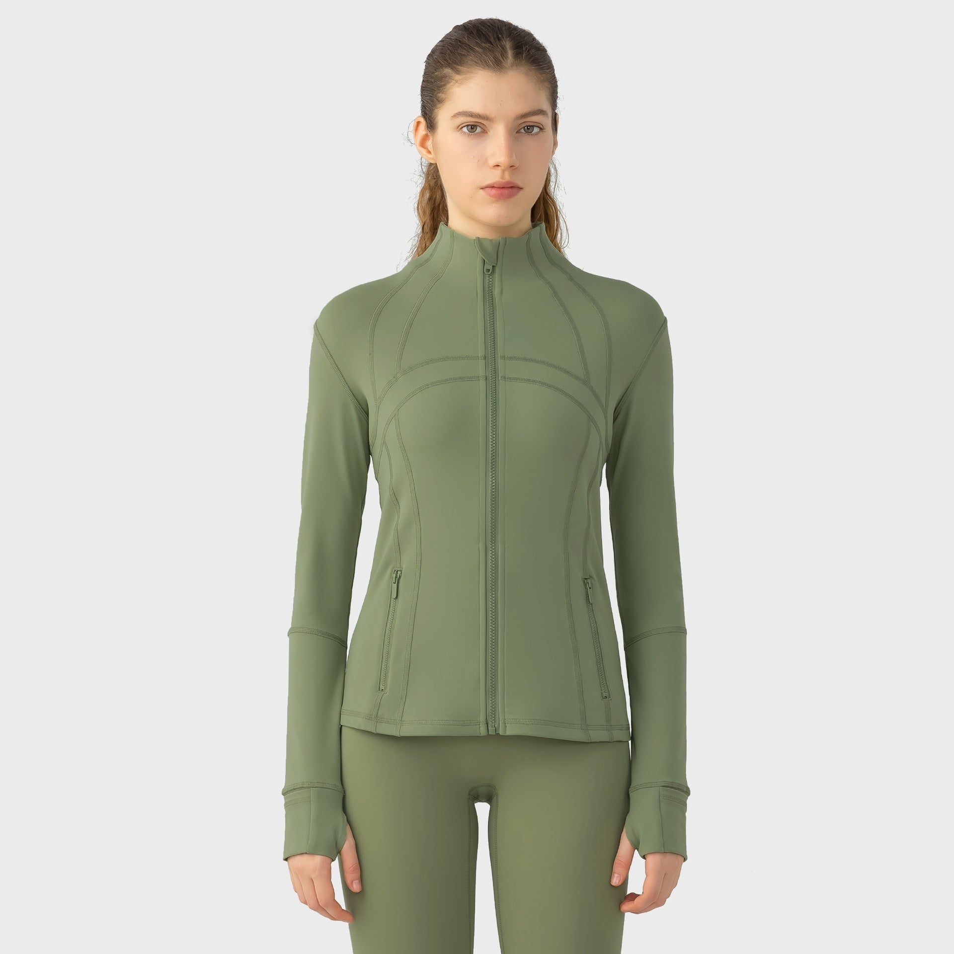 Woman wearing a green athletic jacket and leggings on a white background