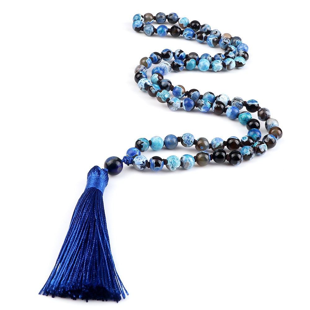 Mala necklace with blue and black beads and a blue tassel on a white background