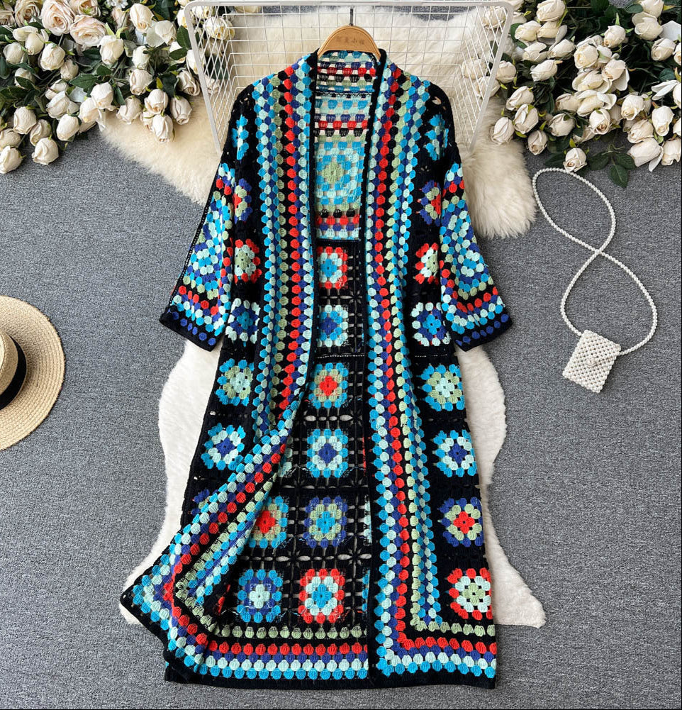 Colorful crochet cardigan on a gray surface with decorative elements