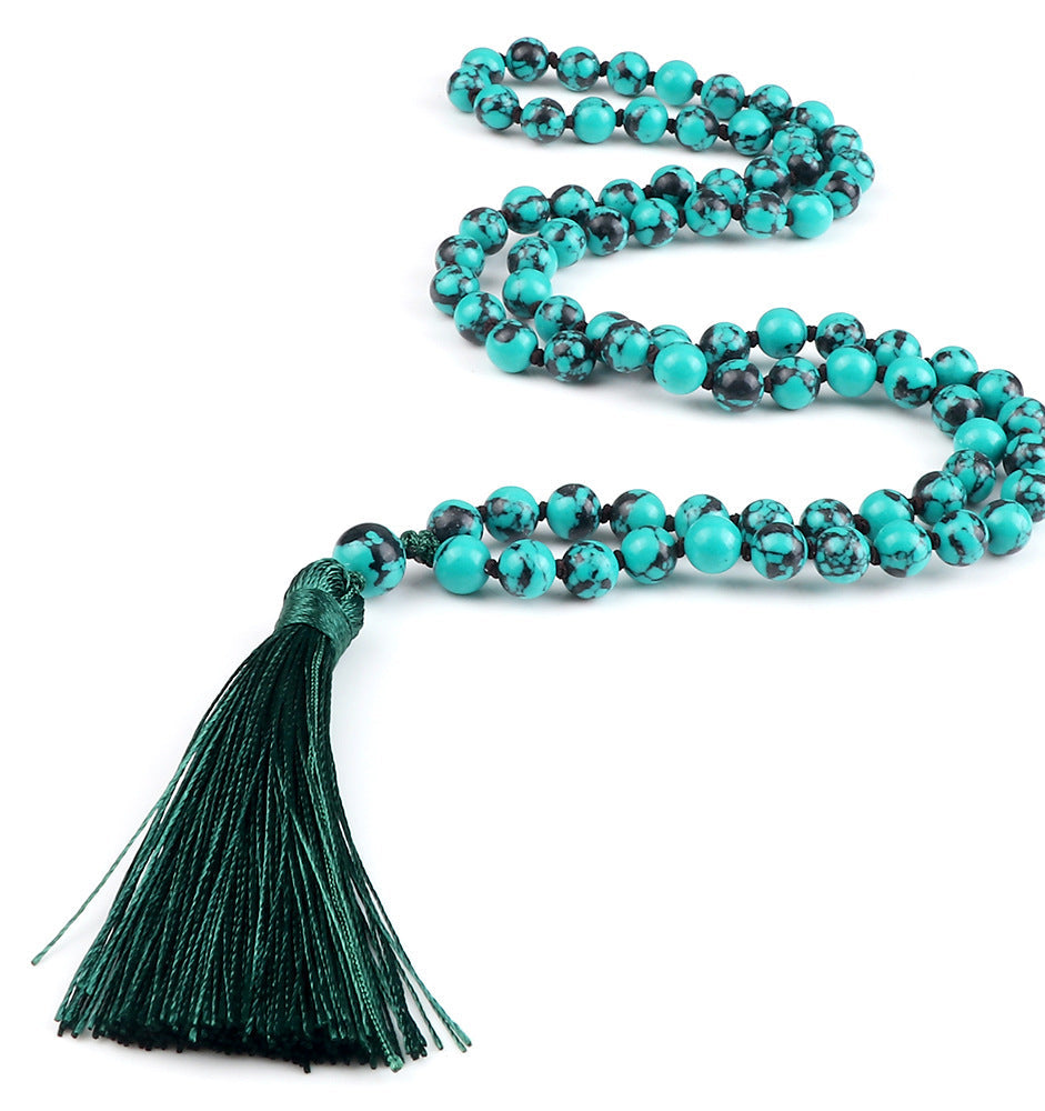 Turquoise beaded necklace with a green tassel on a white background