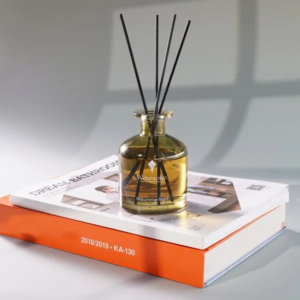 A diffuser with black sticks on a magazine with an orange cover