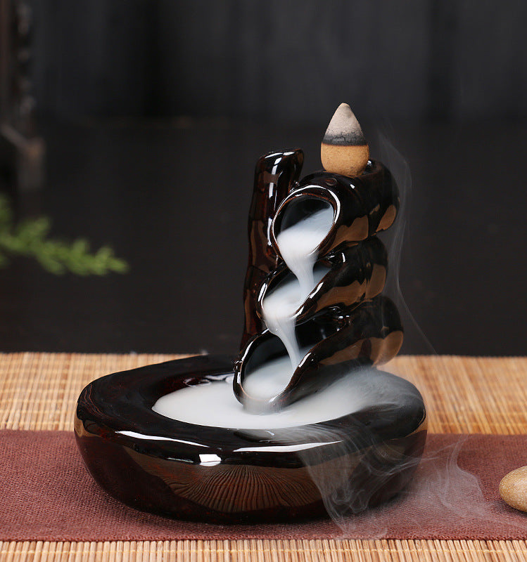Backflow incense burner with smoke on a wooden surface