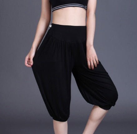 Person wearing black capri pants and white sneakers on a gray background