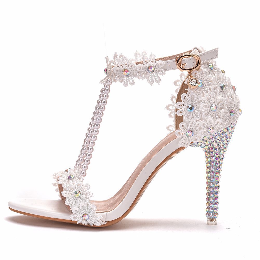 White high-heeled shoe with lace and crystal embellishments on a white background