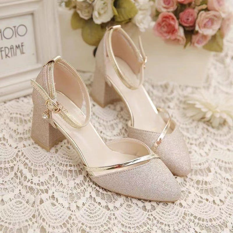 Pair of glittery high-heeled shoes on a lace surface with floral decorations.
