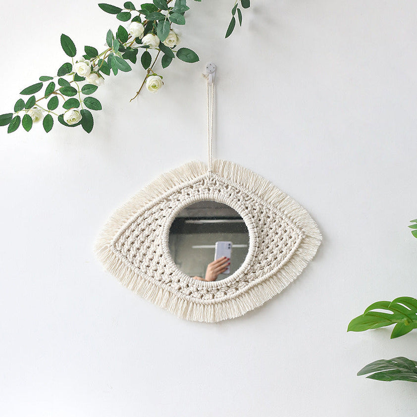 Macrame wall mirror with fringe on a white wall with plants