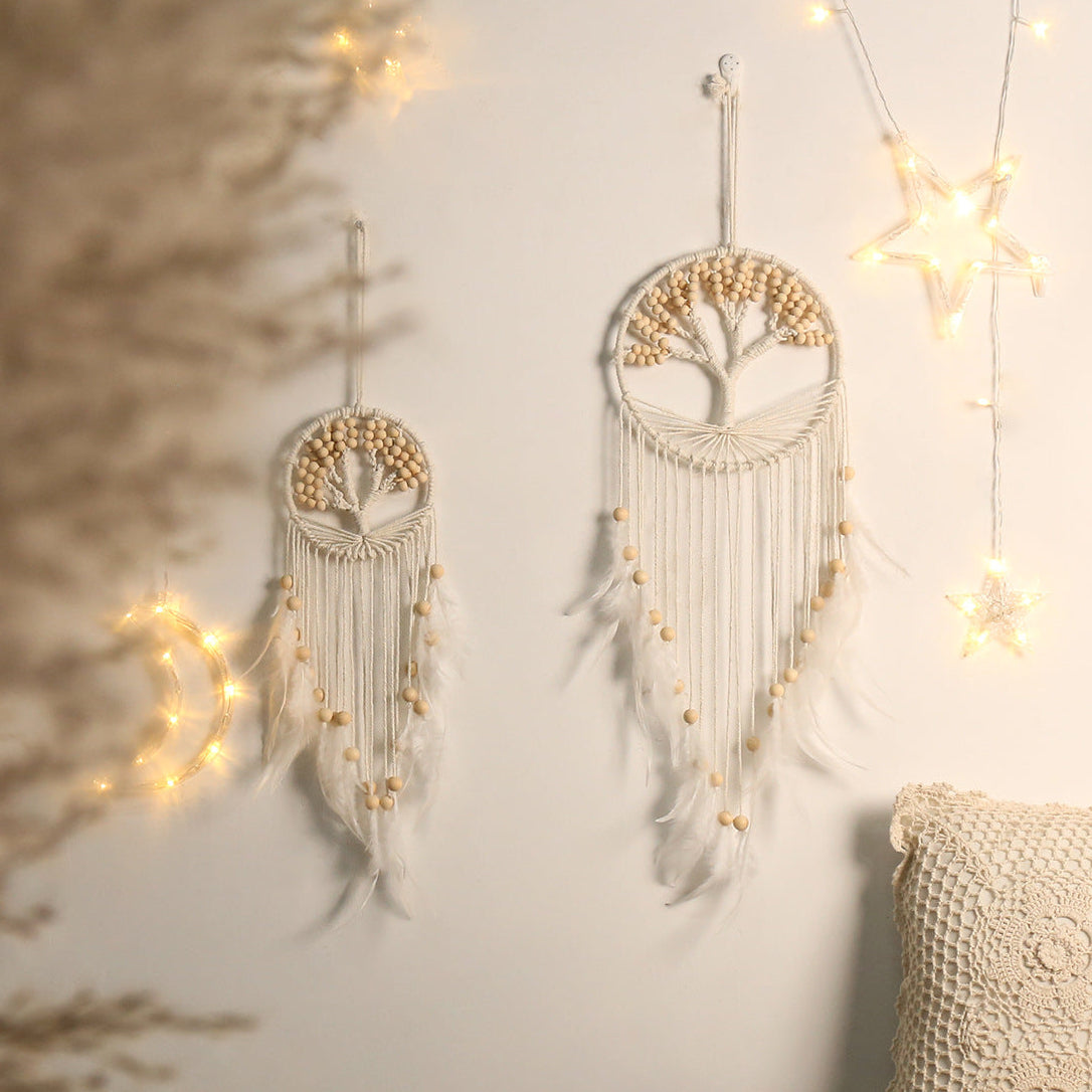 Two tree-themed dream catchers hanging on a wall with string lights.