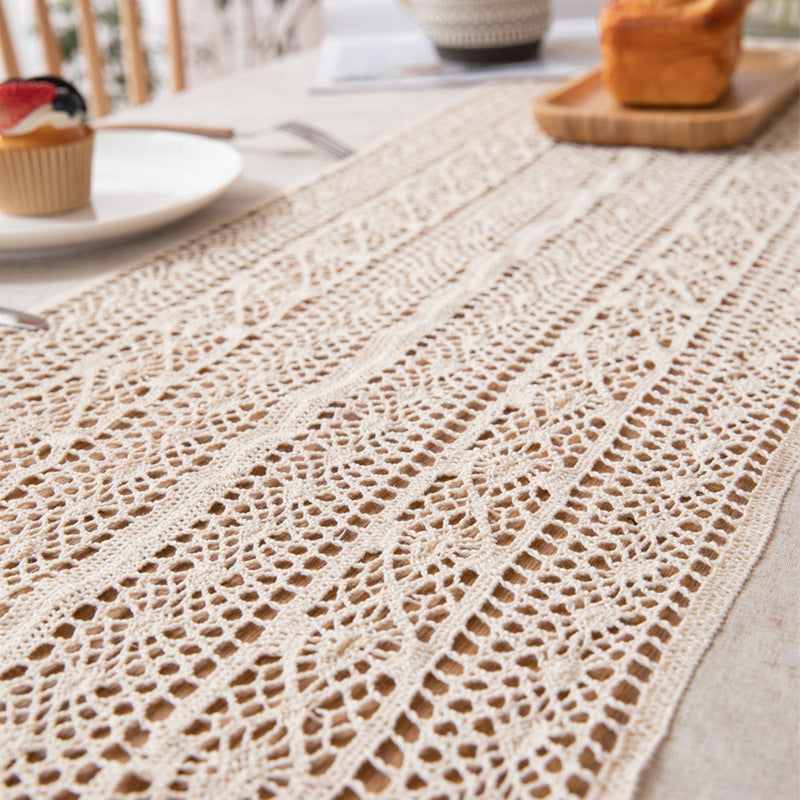Beige crochet table runner on a dining table with plates and a basket in the background.