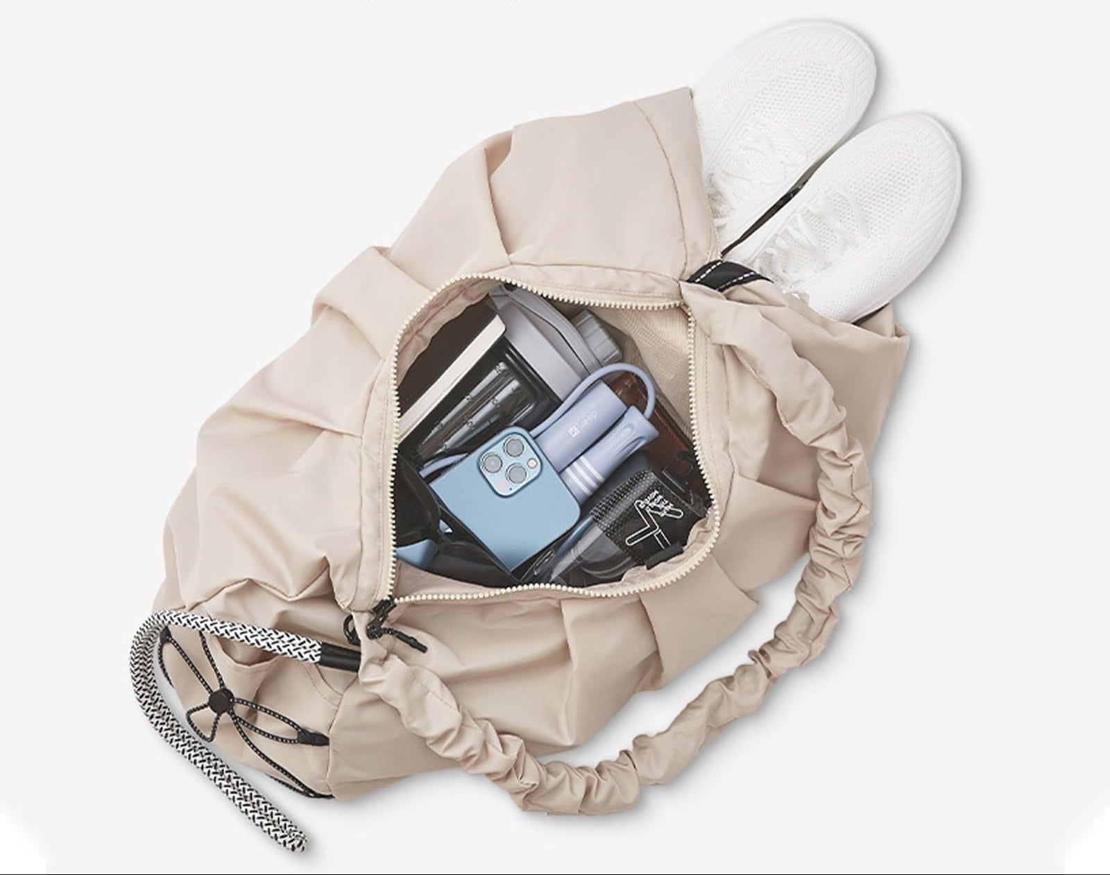 Beige drawstring bag with items inside on a white background