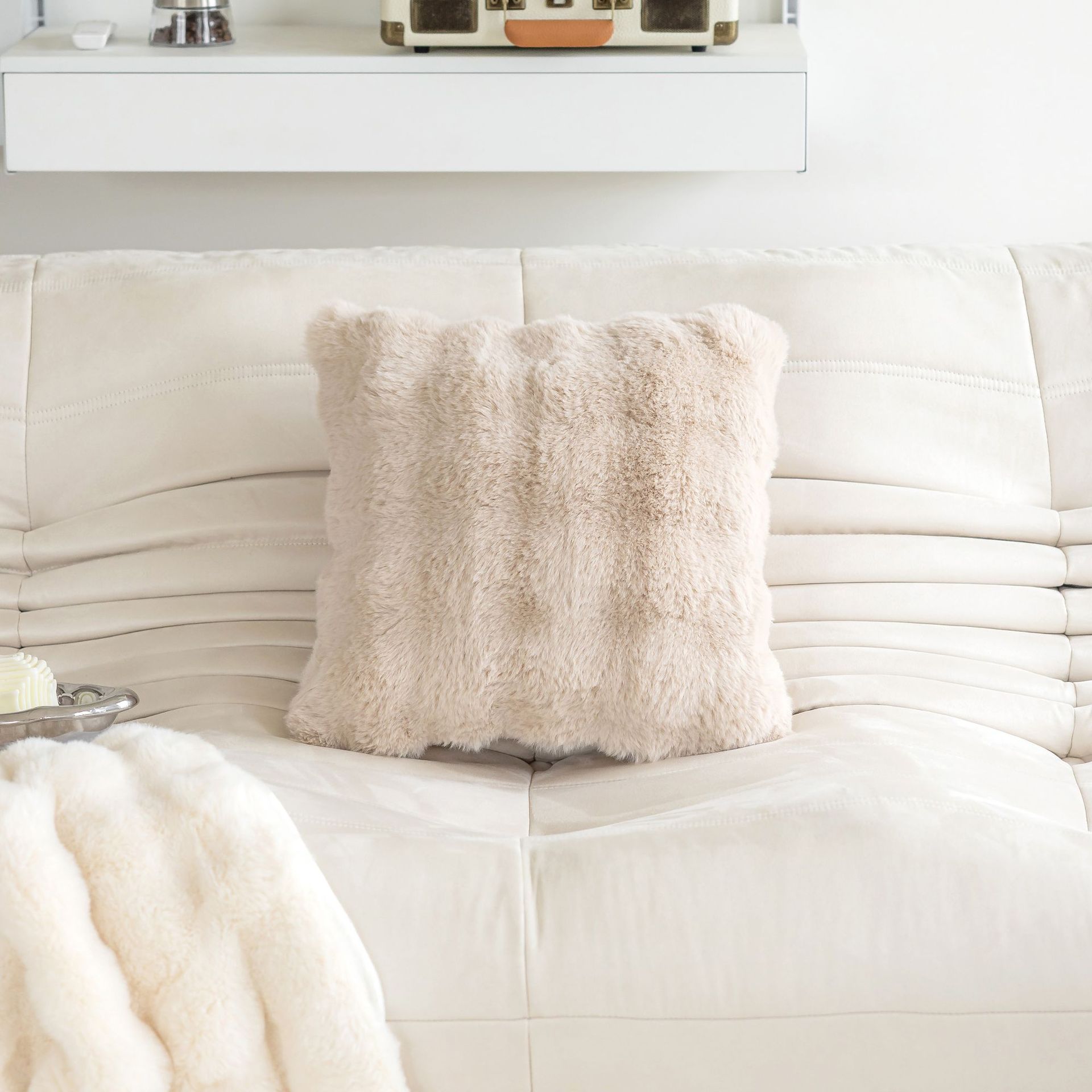 Beige pillow on a white sofa with a white blanket