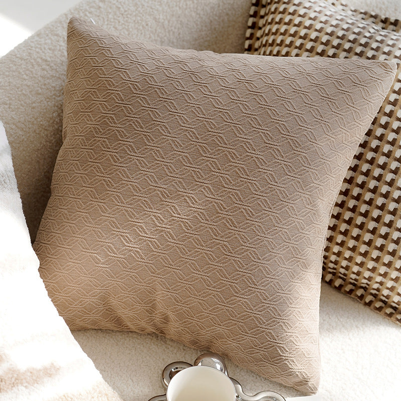 Beige textured pillow on a couch with a neutral background