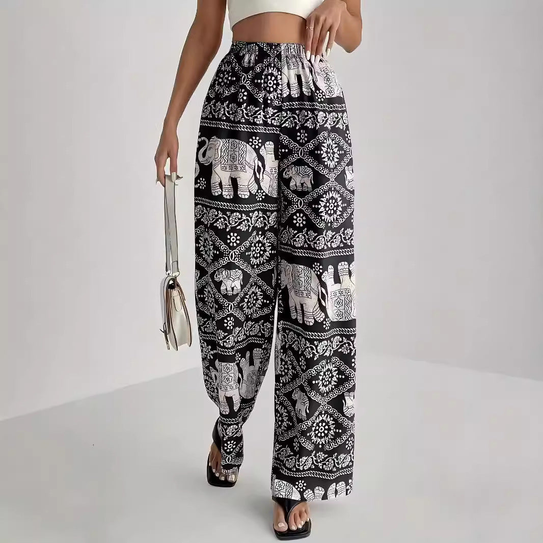 Person wearing black and white patterned pants with elephants on a plain background