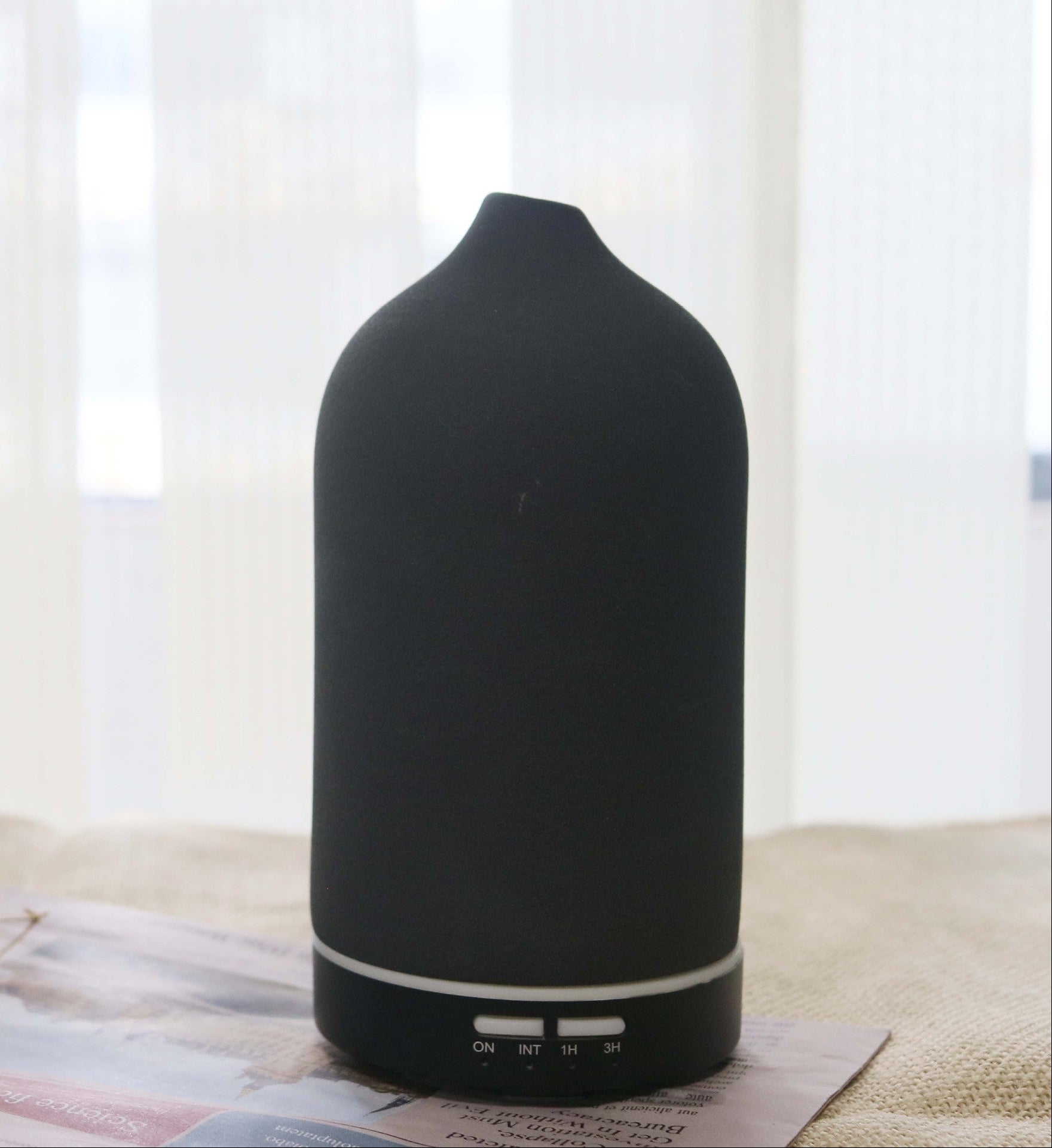 Black essential oil diffuser on a surface with a light background