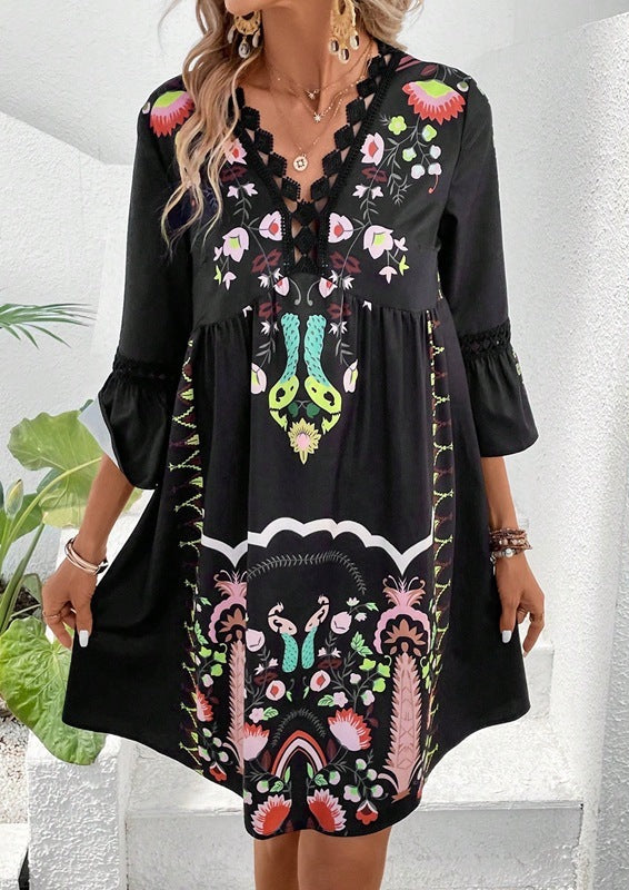 Black dress with colorful embroidery worn by a woman, surrounded by other embroidered dresses.