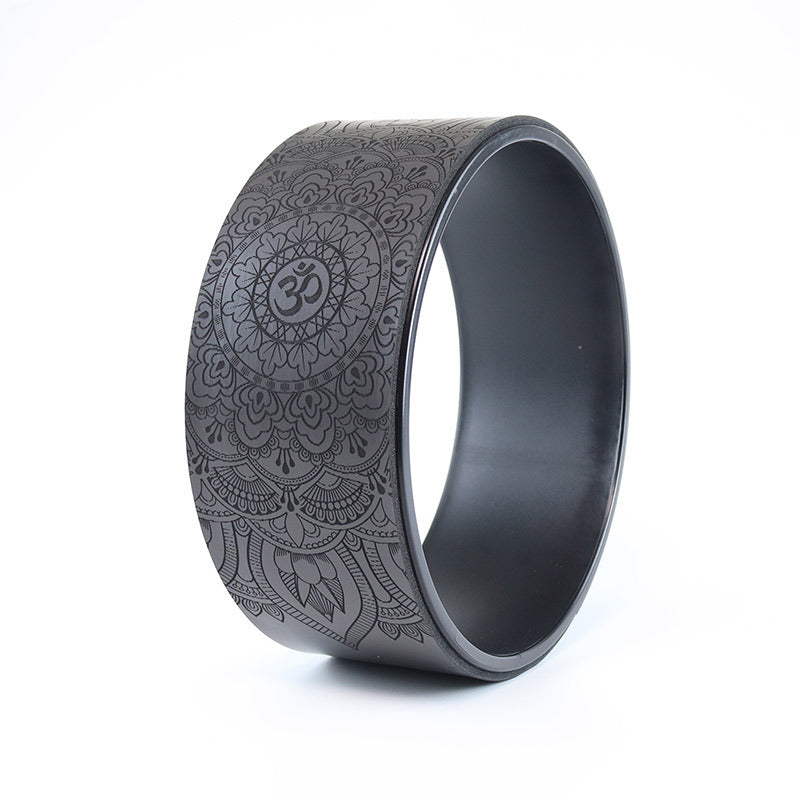 Black yoga wheel with intricate patterns on a white background