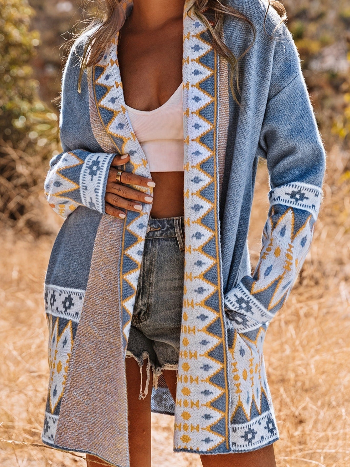 Person wearing a patterned cardigan with a blurred natural background