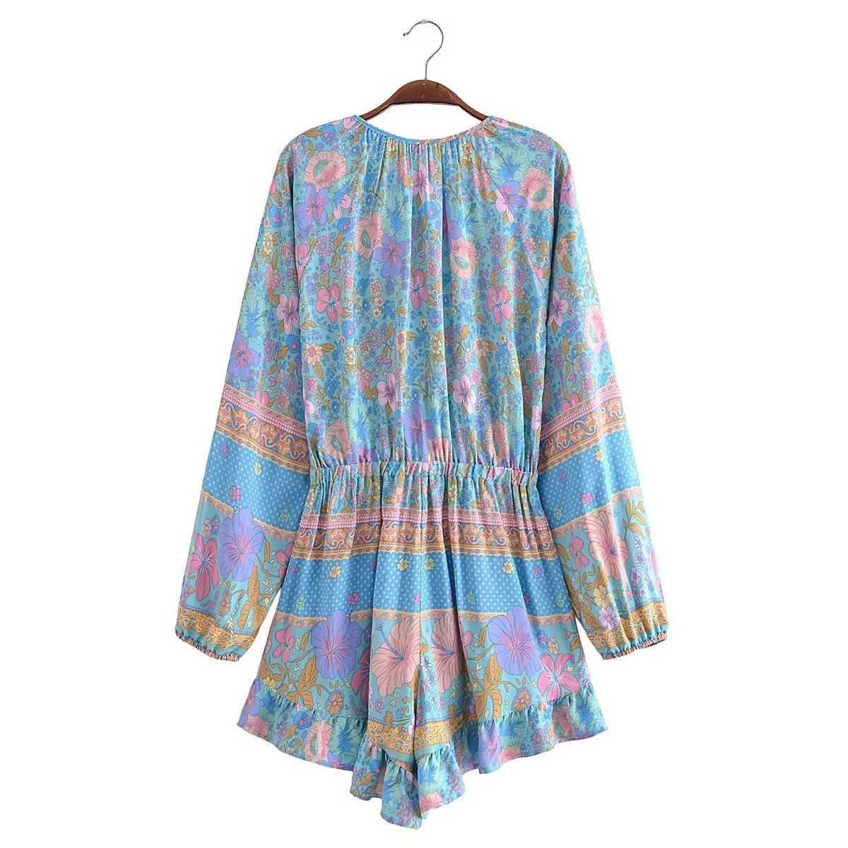 Colorful floral dress on a hanger against a white background