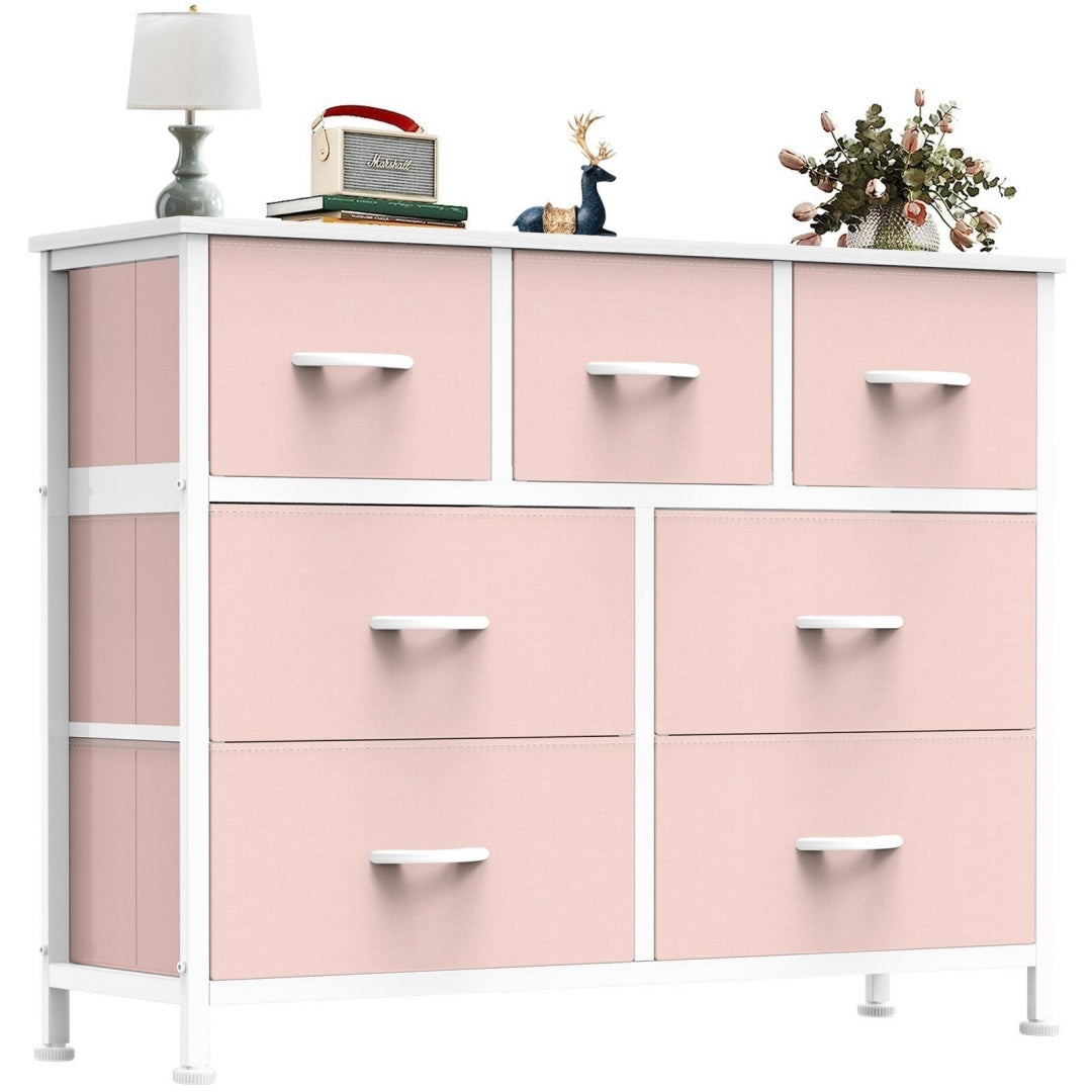Pink dresser with multiple drawers and decorative items on a white background