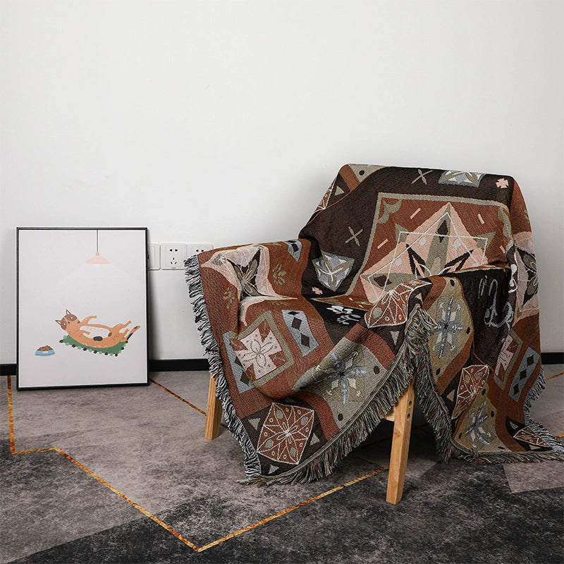 Decorative quilt with geometric pattern draped over a chair in a room with a rug and wall art.