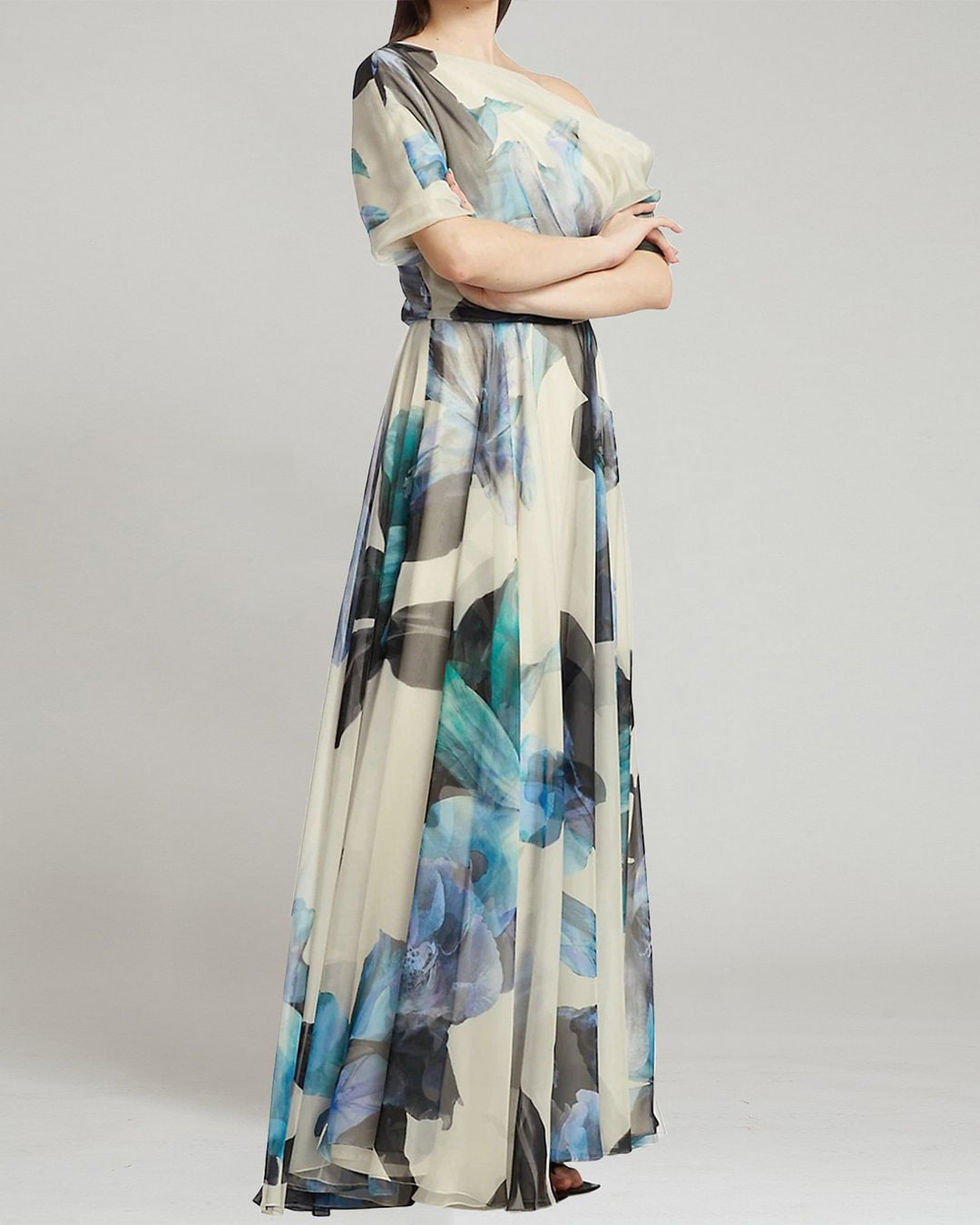 Woman wearing a long, floral-patterned dress on a plain background