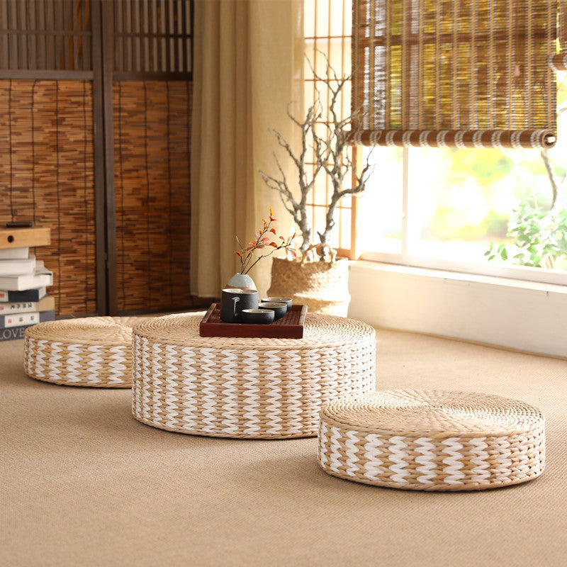Woven ottomans and a small table in a room with a window and decorative elements.