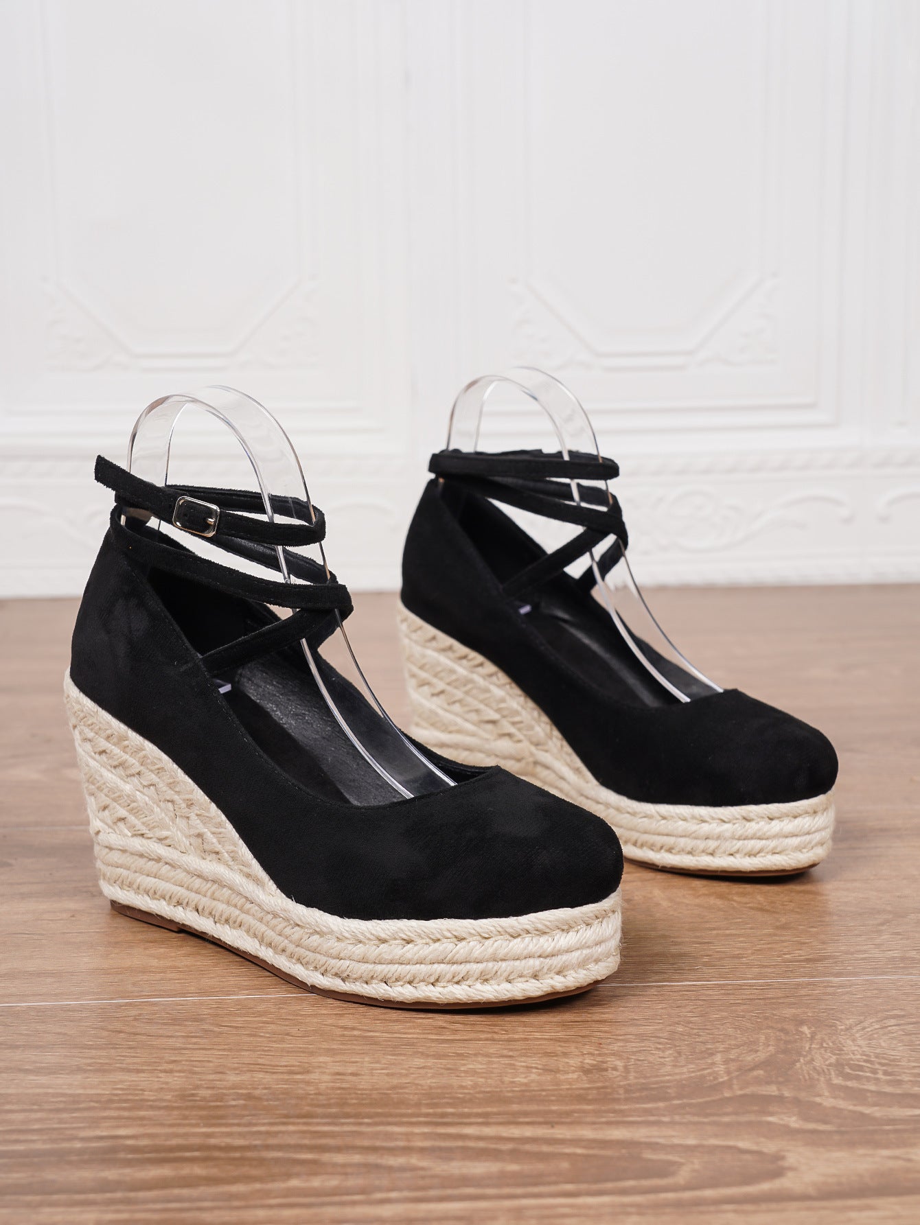 Black wedge sandals with espadrille soles on a wooden surface.