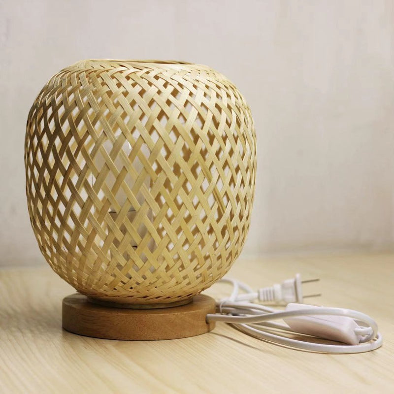 Woven bamboo lamp with power cord on a wooden surface