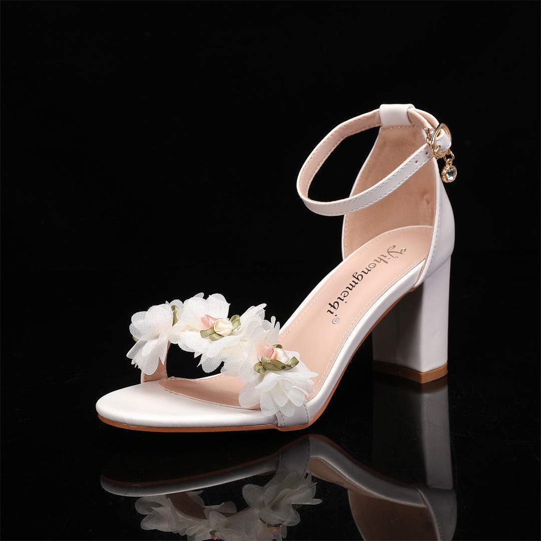 White sandal with floral design on a black background