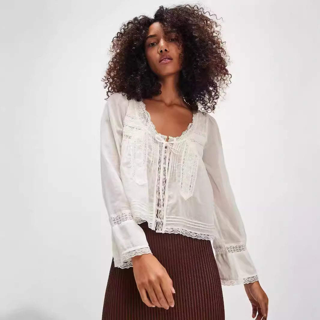 Woman wearing a white lace-trimmed blouse with a plain background