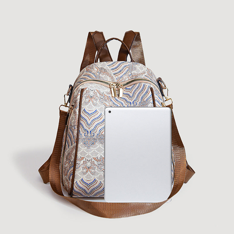 Backpack with a patterned front panel and brown straps on a light gray background