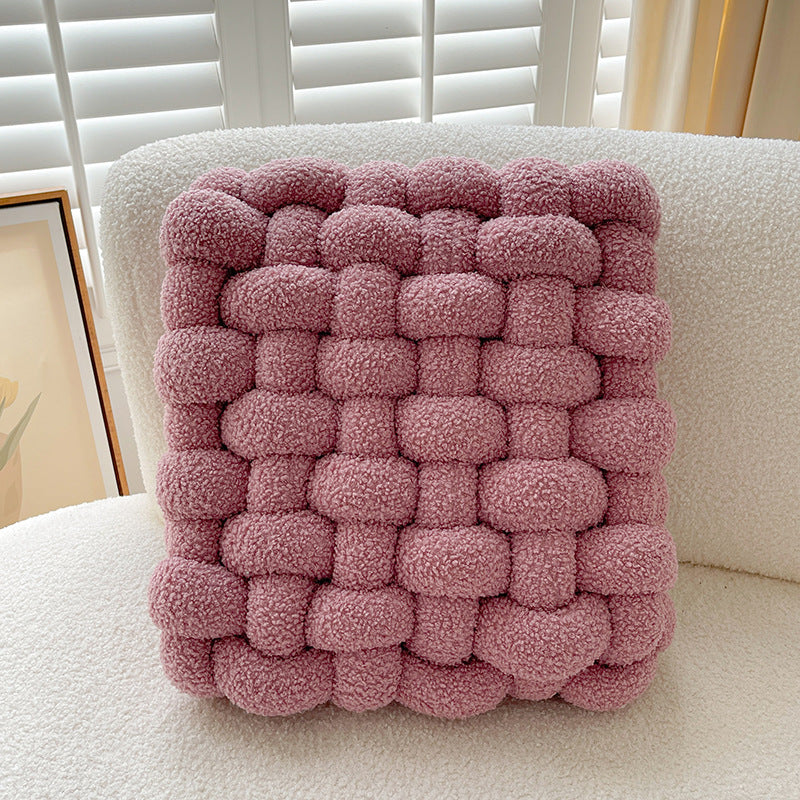 Pink woven cushion on a white chair with a neutral background
