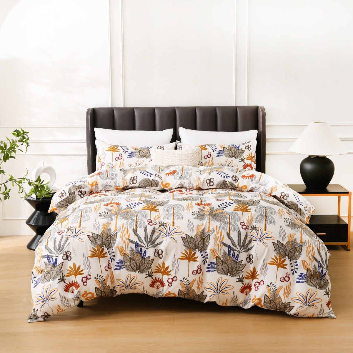 Floral patterned comforter set on a bed with a white wall and plant in the background