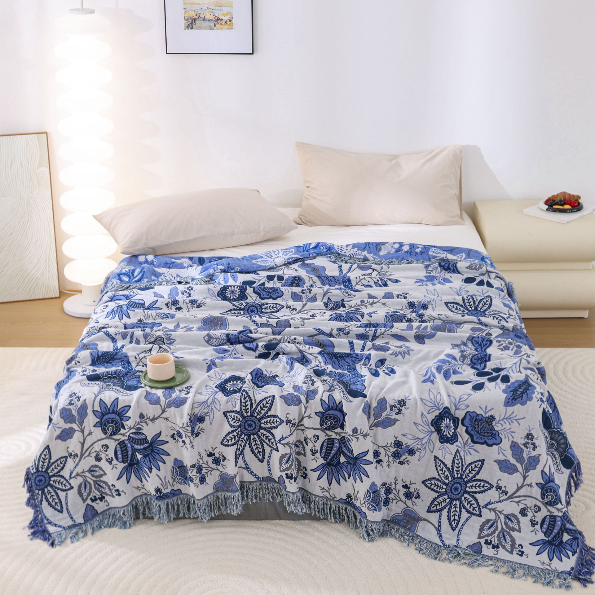 Blue floral patterned throw blanket on a bed in a bedroom setting.